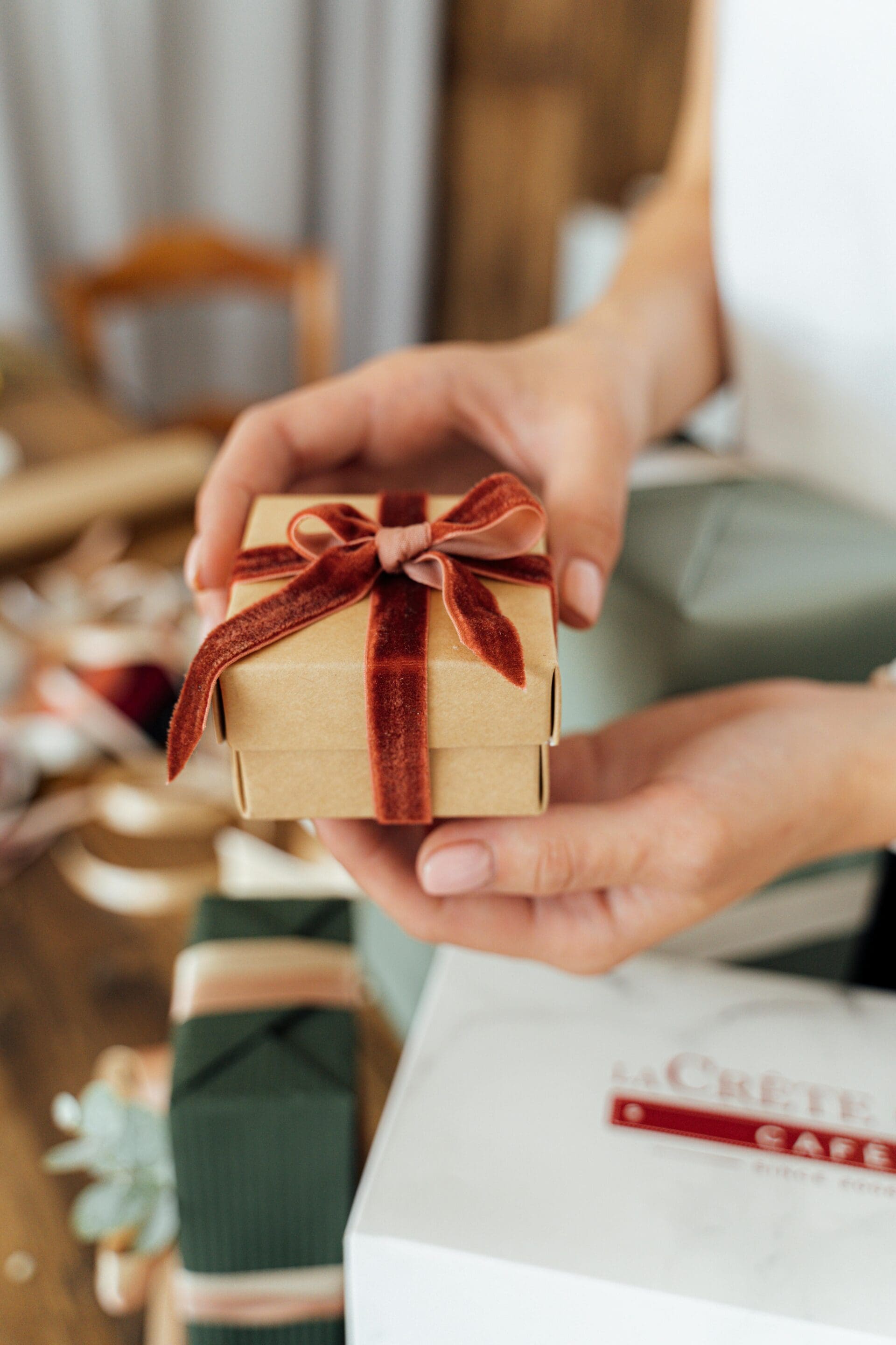 Close-up of a handmade gift box with a velvet ribbon bow held gently in hands, conveying warmth and care.